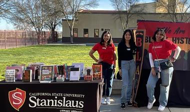 Students stand near a table filled with books on display.