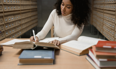 Person in a library writing in a notebook