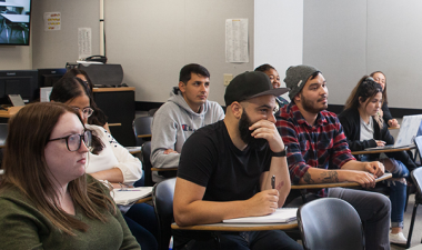 Students seated inside a classroom listen to a lecture.