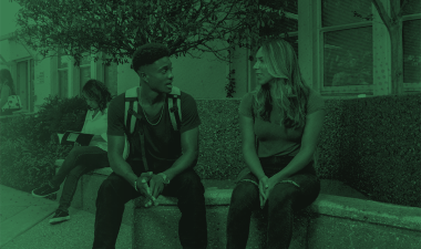 Two students sitting outdoors talking.