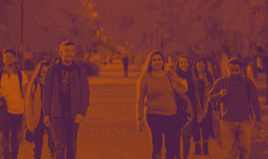 A large group of students walking outdoors on campus.