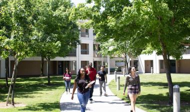 photo of campus housing with trees and students