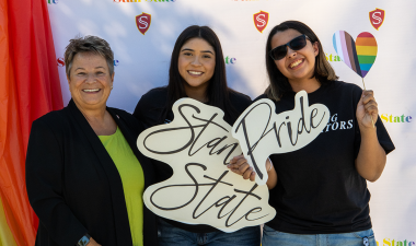 Interim President Sue Borrego poses with two students at the LGBTQ+ Block Party.