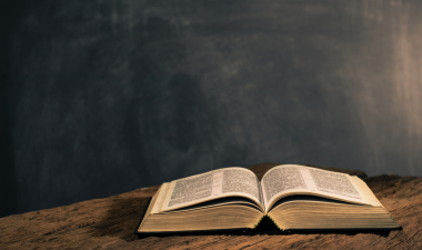 a bible on a desk with a chalk board in the background.