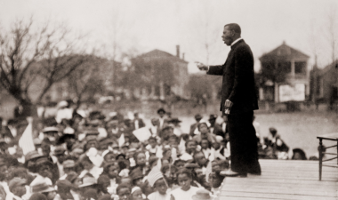a man on stage giving a speach to a large crowd.