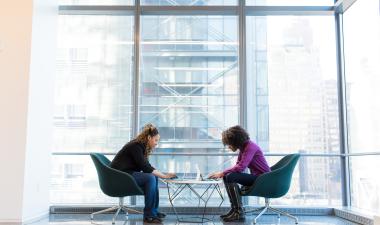 2 people sitting at a table communicating over work.