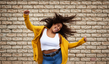 a woman dancing in front of a brick wall.