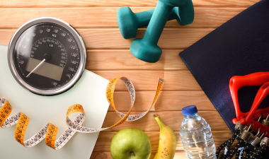a scale, measuring tape, and weights referring to a healthy lifestyle.
