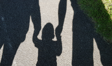 shadows on the ground showing parents holding a childs hands