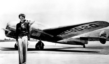 Amelia Earhart standing in front of her plane.