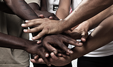 a close up view of a group of hands breaking after a meeting.