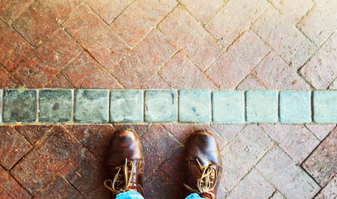 looking down at a pair of feet standing in front of a line in the brick design.