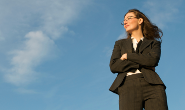 a woman in a business suit standing with her arms crossed