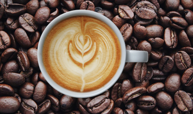 a cup of coffee sitting on coffee beans.