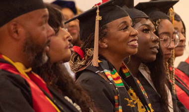 Black students in academic regalia at a graduation celebration. 