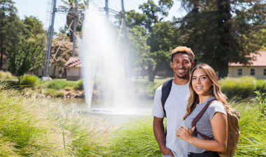 Two Stockton students smiling. Water fountain in the background.