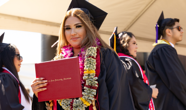 Graduate grips her degree holder at Commencement.