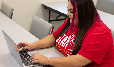 A student works on her laptop at a desk.