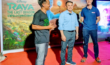 Steve Arounsack stands with two other men in front of a movie poster for "Raya and the Last Dragon."
