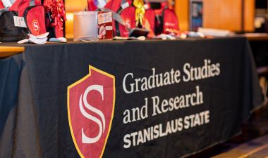 Tabling with giveaway items and logo for Graduate Studies and Research at Stanislaus State