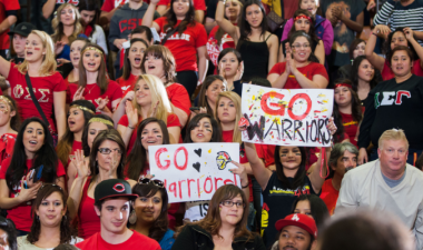 A crowd of students cheers from the bleachers at Stan State homecoming basketball game.