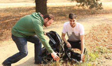 Students outdoors with a trash bag picking up litter