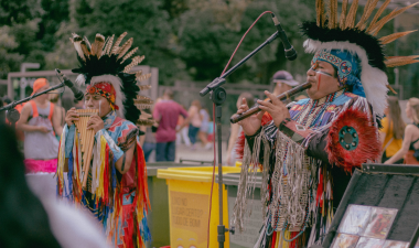 Two men wearing traditional headdresses play musical instruments, showcasing cultural heritage and artistry.