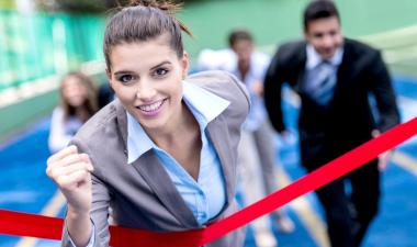 Business woman running across finish line