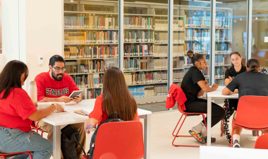 Two groups of students seated at tables studying inside the Library.