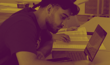 A student works on his laptop while seated at a desk.