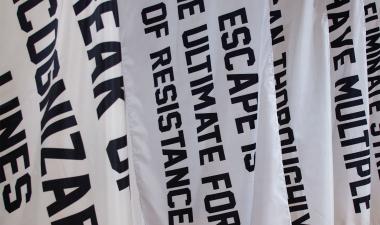 White flags with messages of resistance, adorned in black bold text.