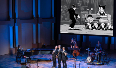 The Queen's Cartoonist performing on stage.