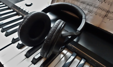 Headphones and music sheets on top of a piano