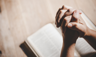 Hands praying over a Bible