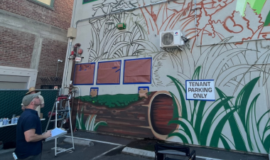 Alexander Ayers paints a mural depicting butterflies and greenery
