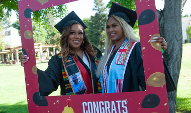 Two graduating students pose for a picture.