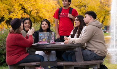 Several students have a discussion while sitting outdoors.
