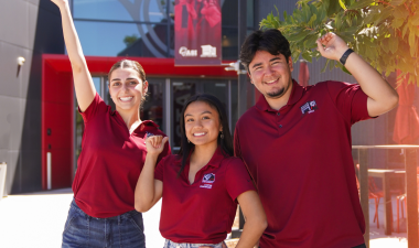 Three students in a group picture by the Student Center's main entrance