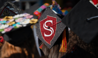 Graduating student with the Stan State shield on their mortar board.