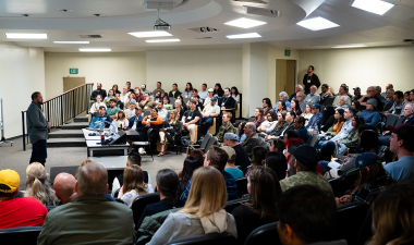 People seated in a large classroom listening to a speaker.