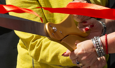 Hands hold scissors during the Willow Hall building's ribbon-cutting ceremony.