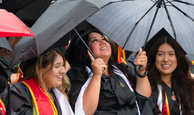 Graduates with umbrellas seated in their regalia at Commencement