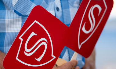 Hands holding fans decorated with the Stan State shield logo.