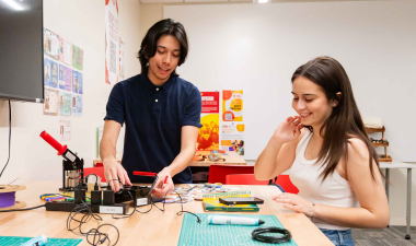 Two Stanislaus State students work together with electronics and tools at a table in a campus lab.