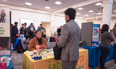 Employers at tables talking with students in professional attire
