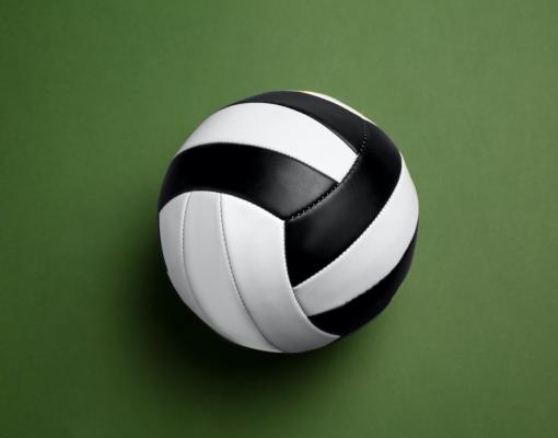 A black and white volleyball. Green background