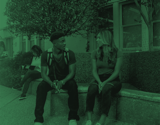 Two students sitting outdoors talking.