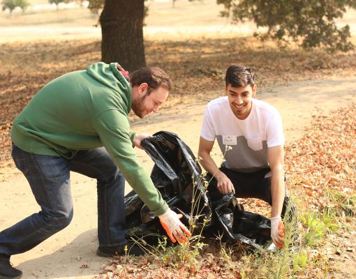 Students outdoors with a trash bag picking up litter