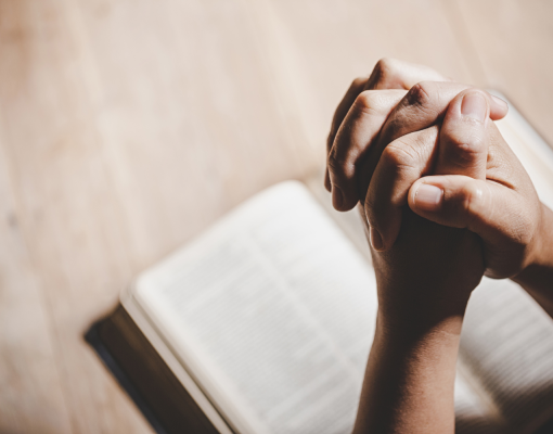 Hands praying over a Bible