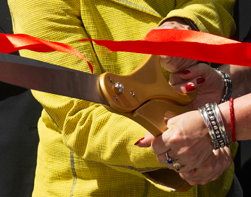 Hands hold scissors during the Willow Hall building's ribbon-cutting ceremony.